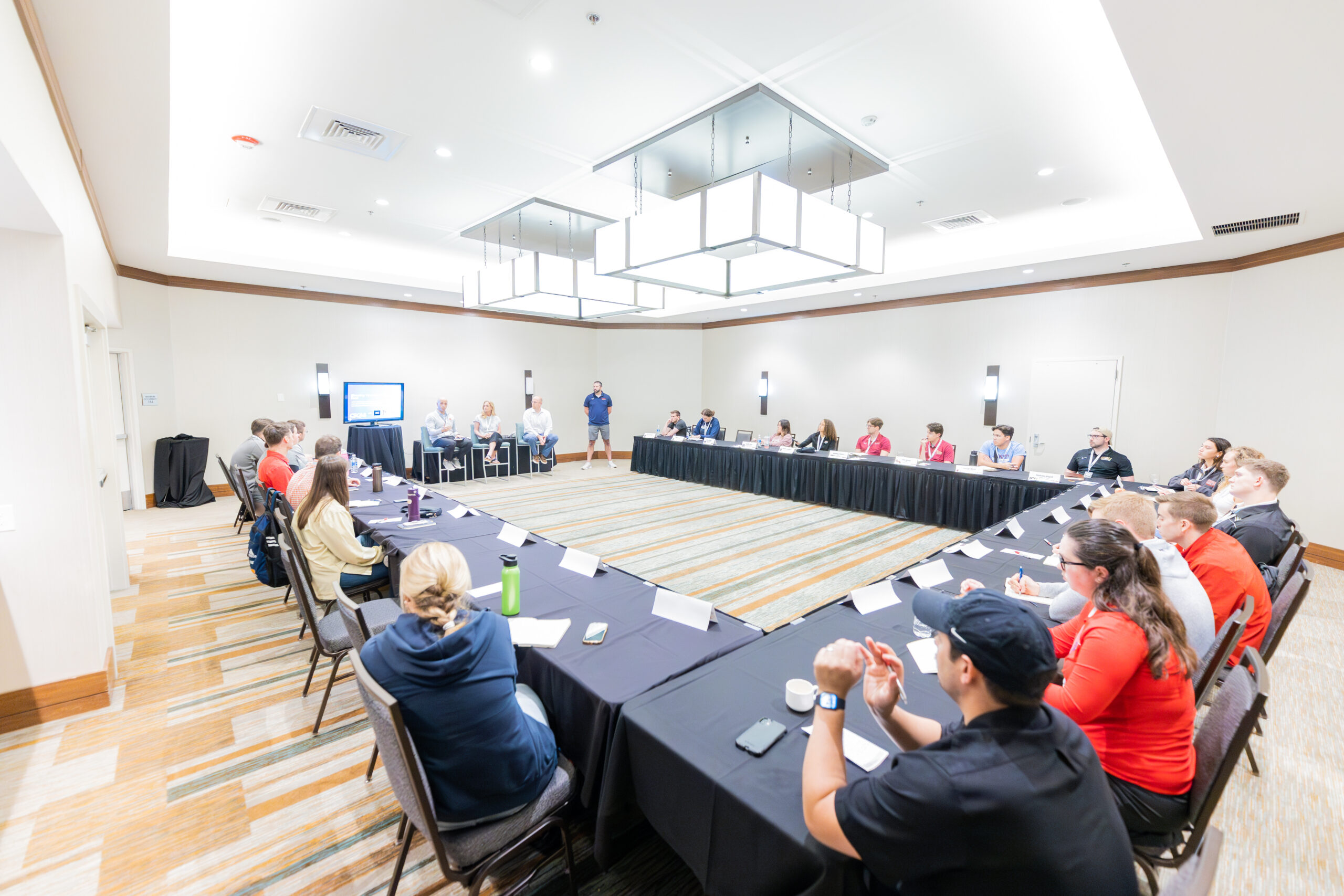 Large business meeting around U-shaped table