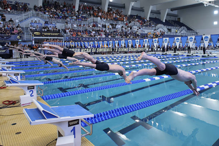 Swimmers diving into pool at swim meet